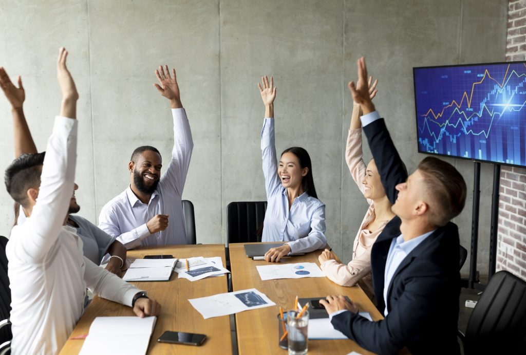 Business Training. Group Of Happy Colleagues Raising Hands At Meeting In Office